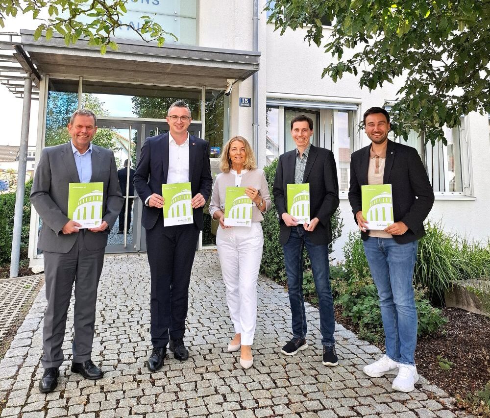 Gruppenbild vor Gebäude mit Geschäftsbericht