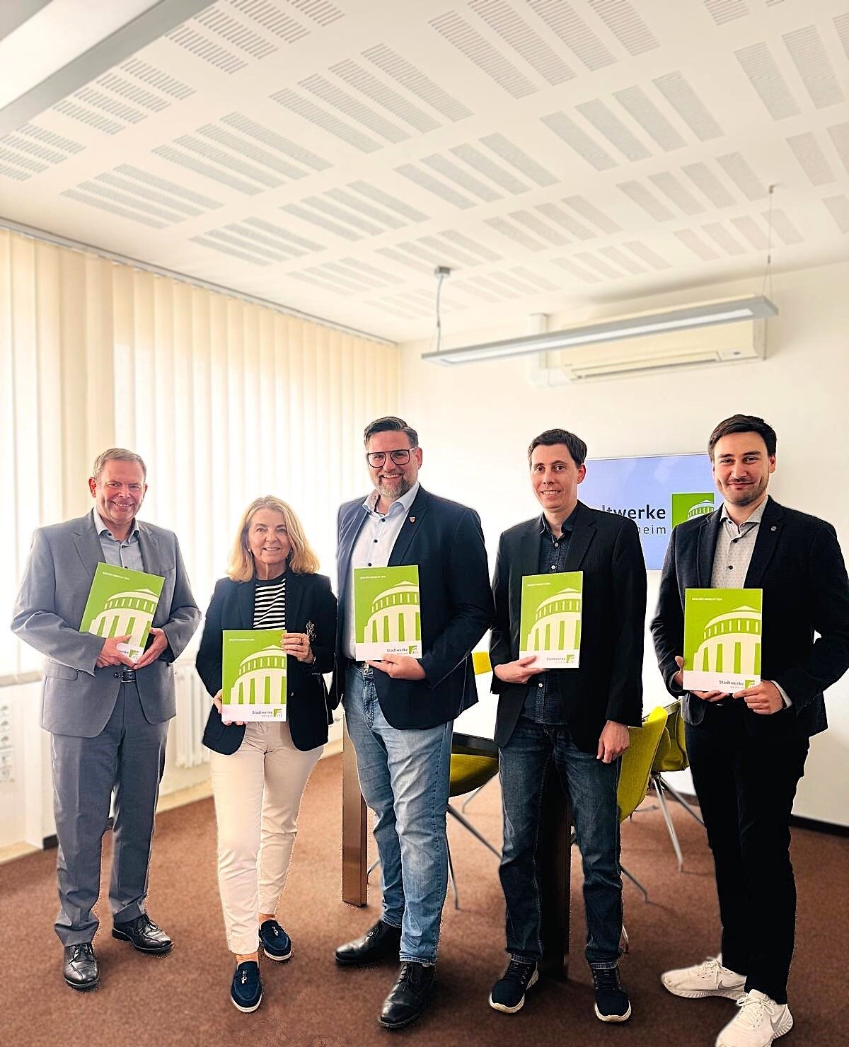 Gruppenbild Geschäftsleitung und Aufsichtsratsvorsitzender mit Geschäftsbericht